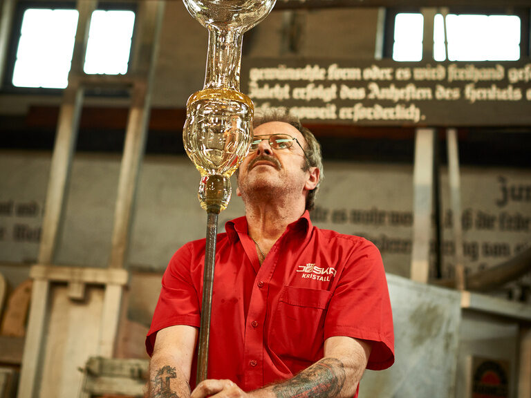 Ein Mann mit einem frischgeblasenen Kunstwerk aus Glas.